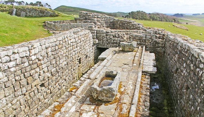 Housesteads Roman Fort latrines with stone seating and drainage system, Northumberland, England.