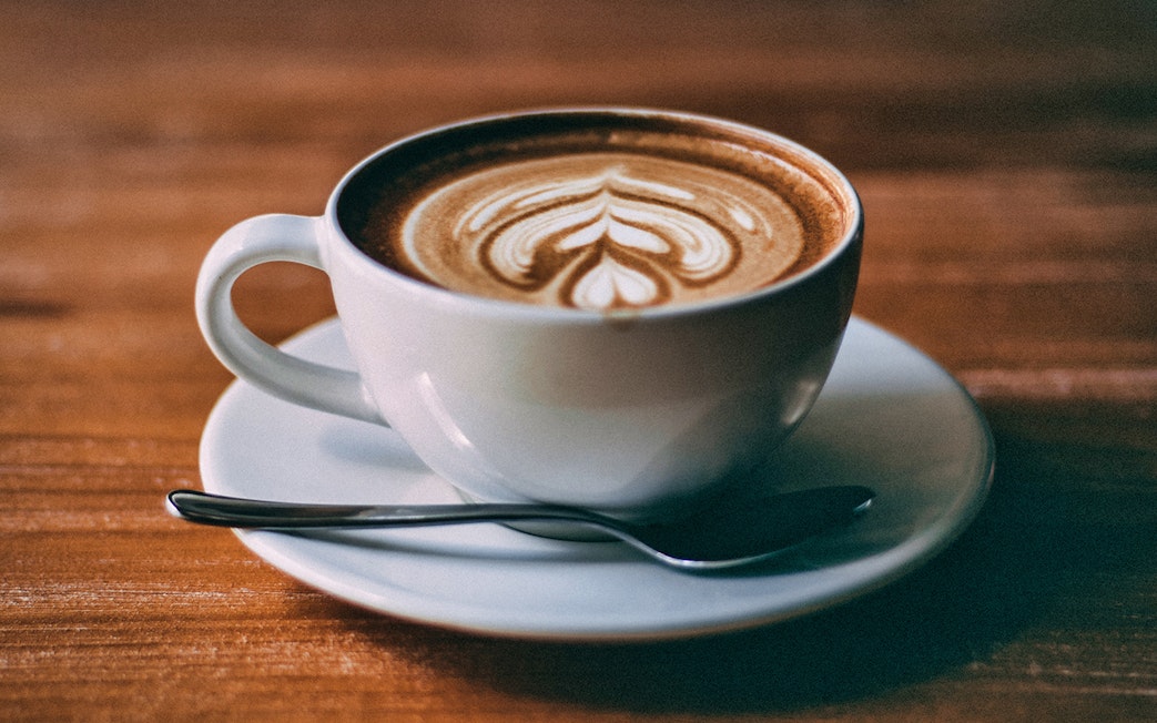 Cup of coffee with latte art served on a wooden table in Hamburg.