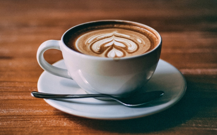 Cup of coffee with latte art served on a wooden table in Hamburg.