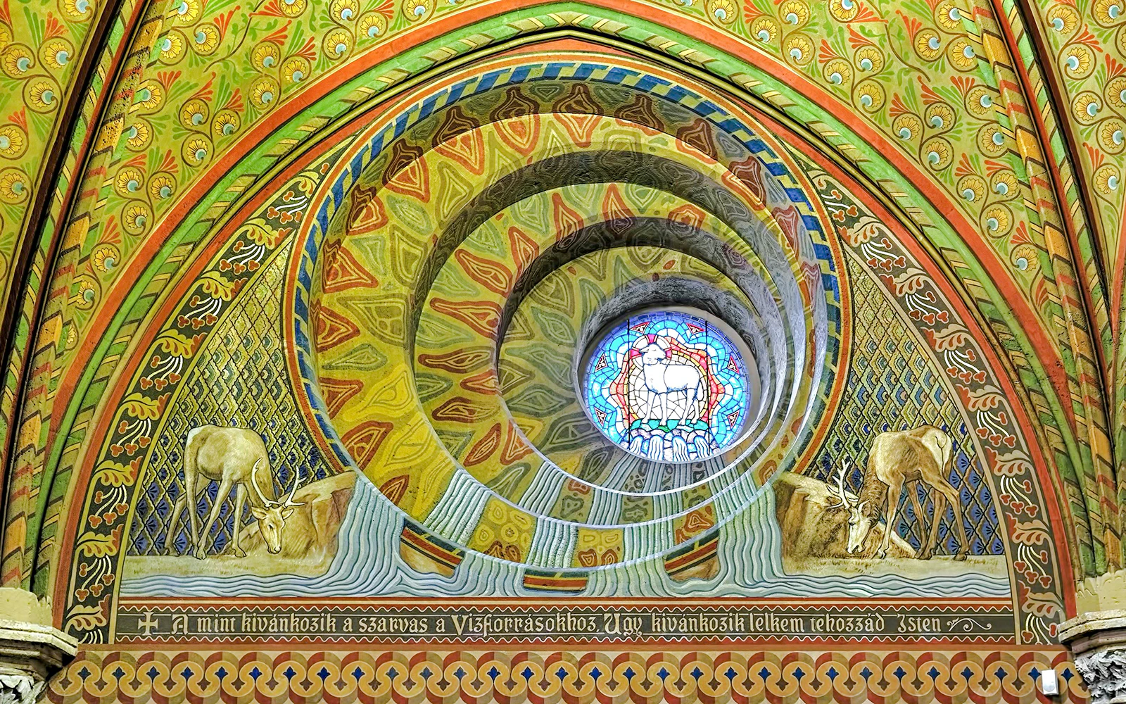 Round window in Matthias Church tower, Budapest, with colorful stained glass and intricate frescoes.