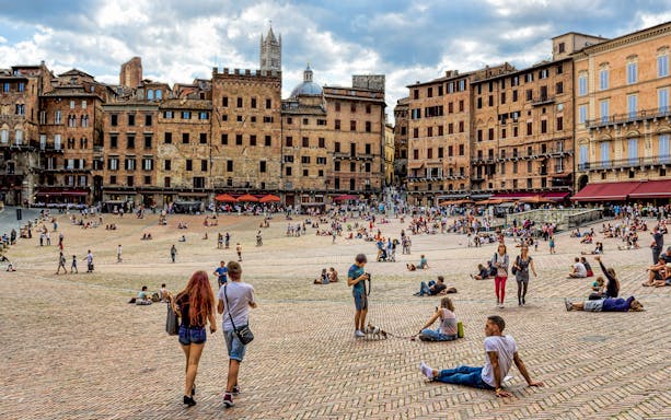 Siena's Piazza del Campo with people relaxing and walking, part of Pisa, Siena, San Gimignano & Chianti tour.
