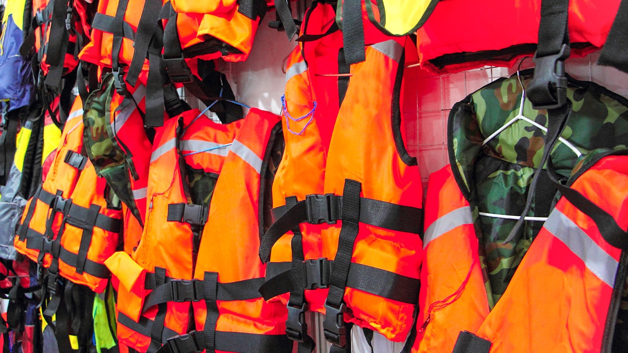 Bright orange life jackets hanging on display.