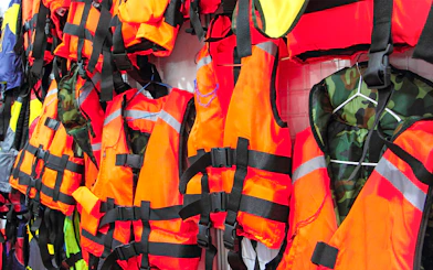Bright orange life jackets hanging on display.
