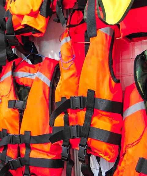 Bright orange life jackets hanging on display.