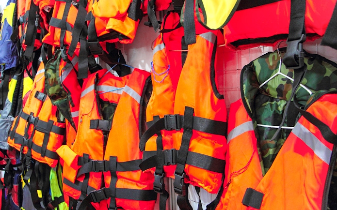 Bright orange life jackets hanging on display.