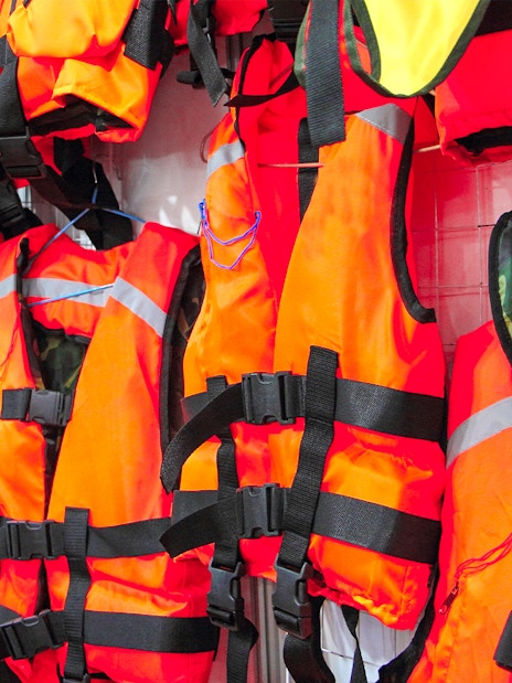 Bright orange life jackets hanging on display.