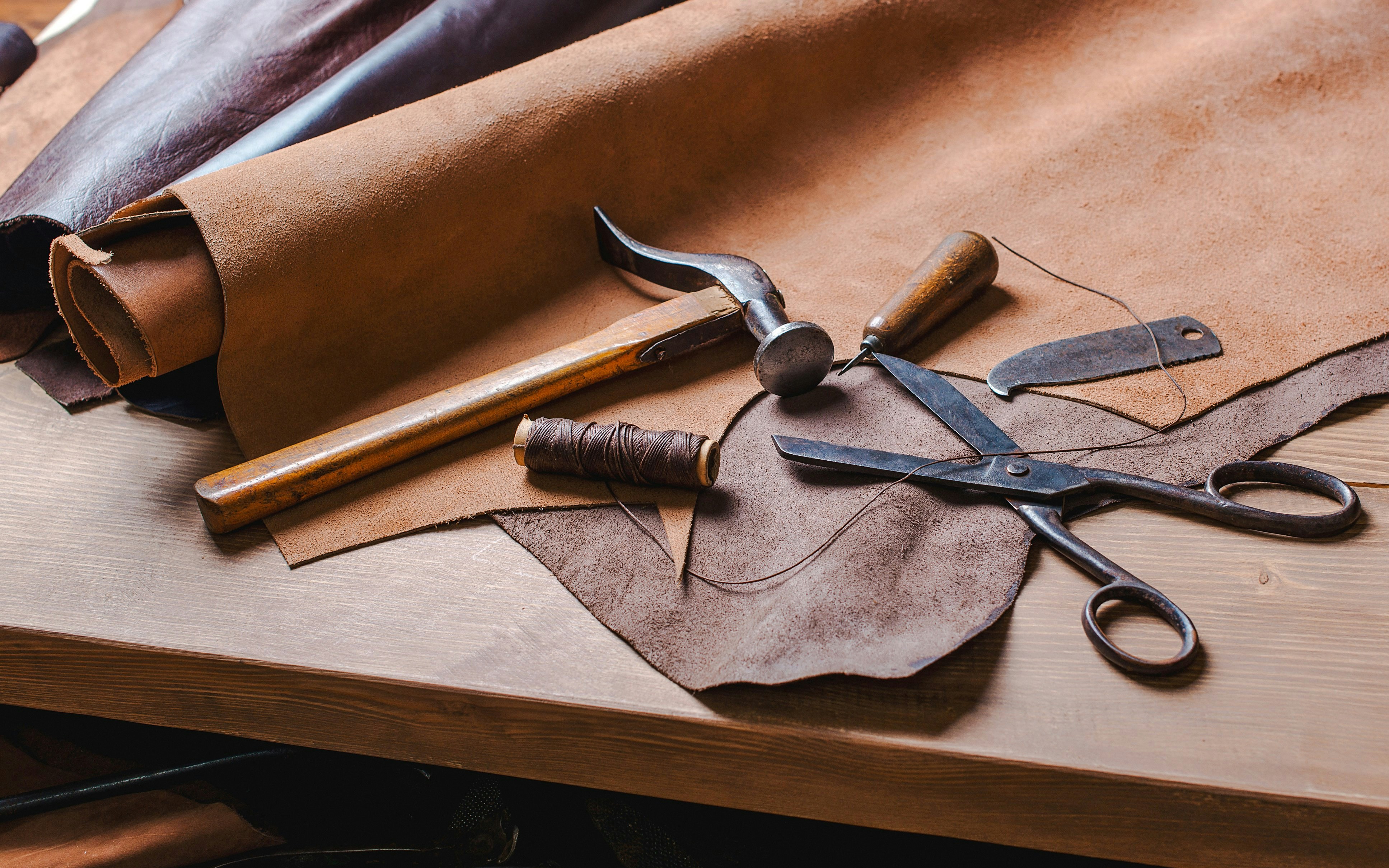 Leather crafting tools and materials on a workshop table.