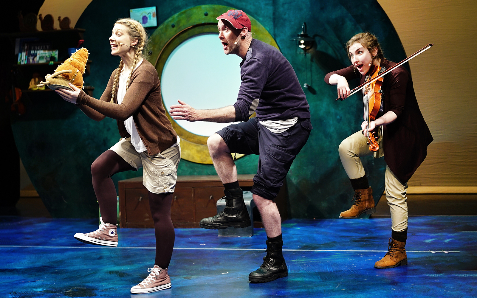 Actors performing "The Snail and the Whale" on stage with a violinist.