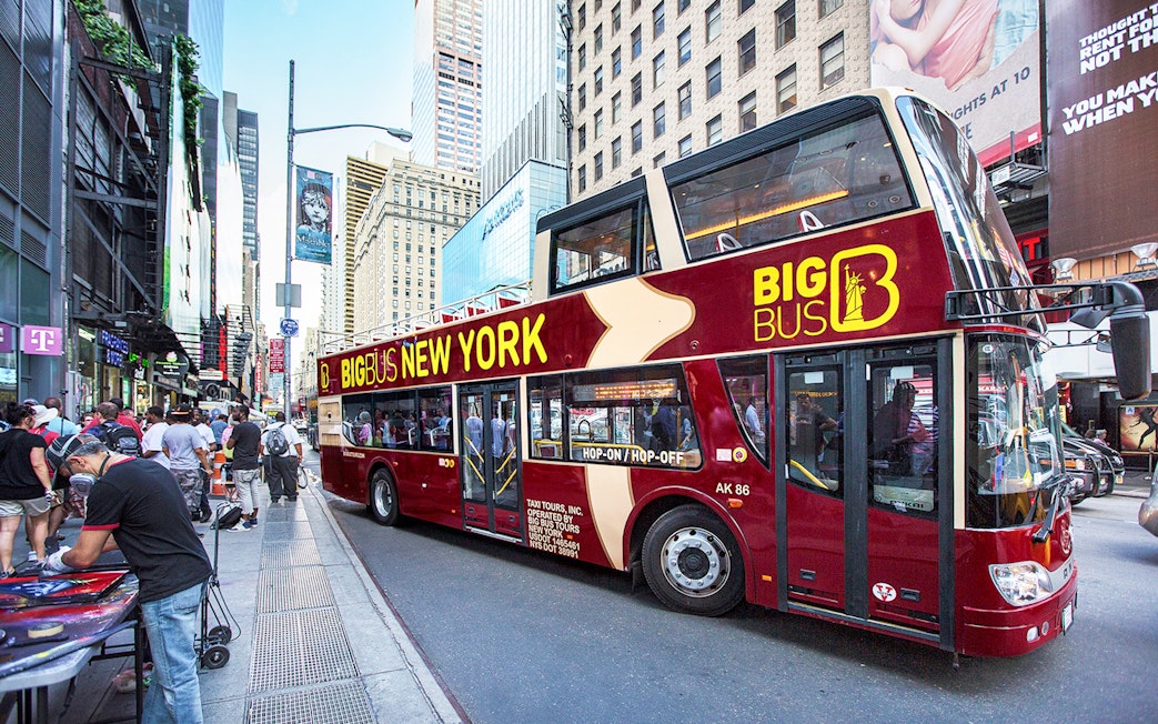 Big Bus New York tour bus on a busy city street with skyscrapers.