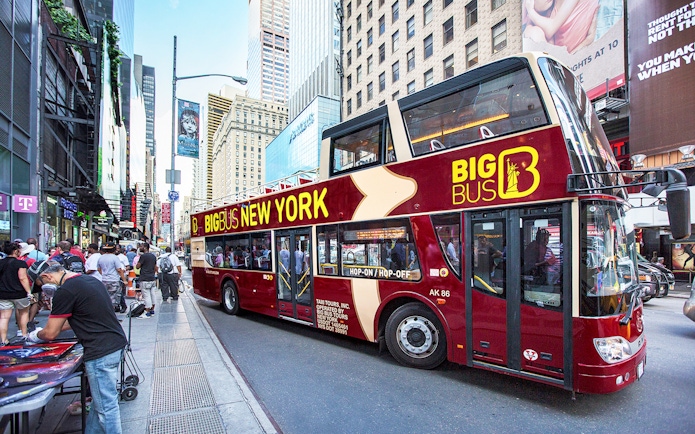 Big Bus New York tour bus on a busy city street with skyscrapers.
