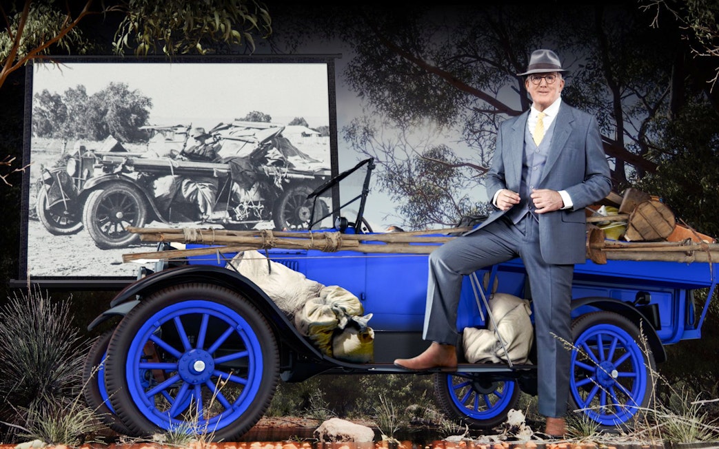 Man in suit with vintage car at Alice Springs Royal Flying Doctor Service exhibit.