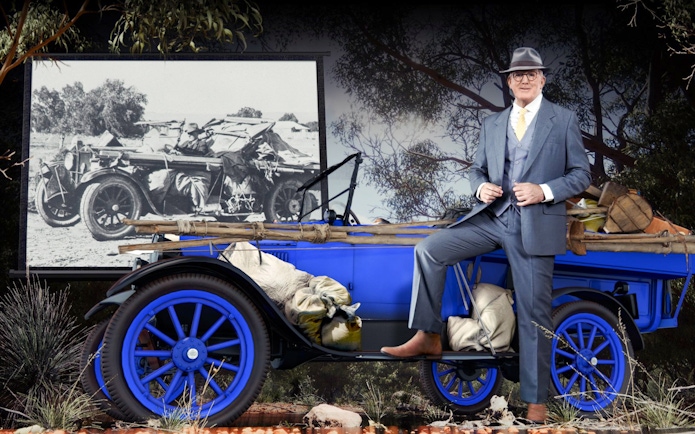 Man in suit with vintage car at Alice Springs Royal Flying Doctor Service exhibit.