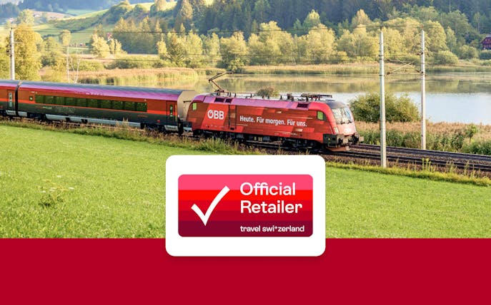 Eurail train traveling through scenic countryside with lake and forest views.