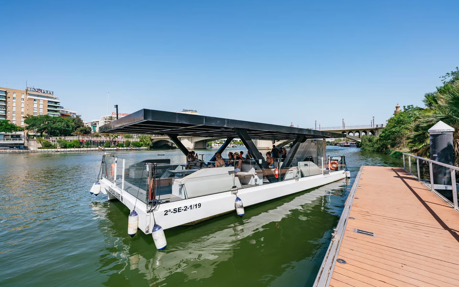 Eco-friendly cruise boat docked on Guadalquivir River, Seville, Spain.