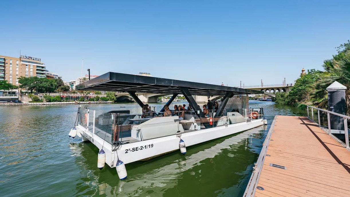 Eco-friendly cruise boat docked on Guadalquivir River, Seville, Spain.