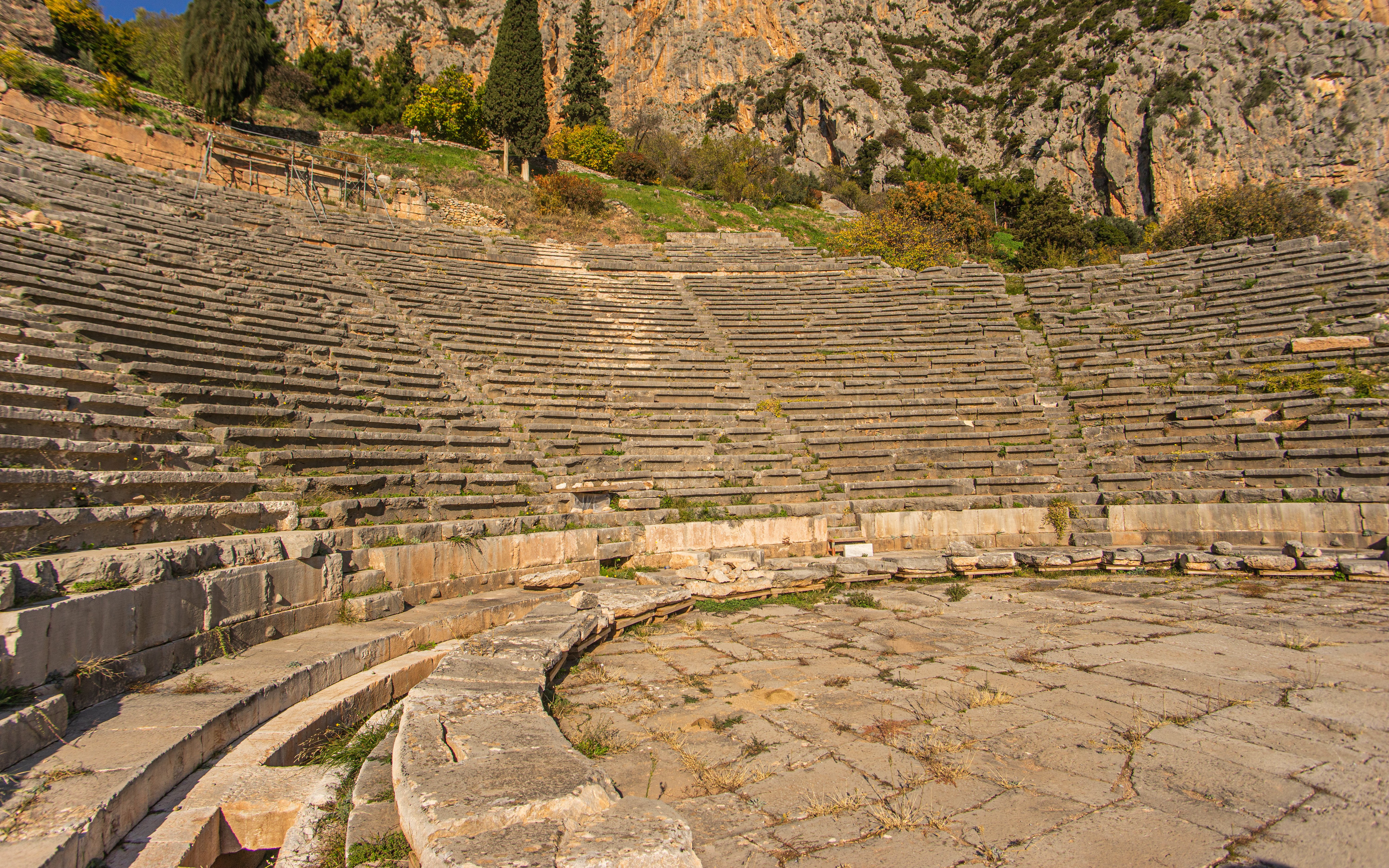 Theater of Delphi stone seating with mountainous backdrop in Greece.