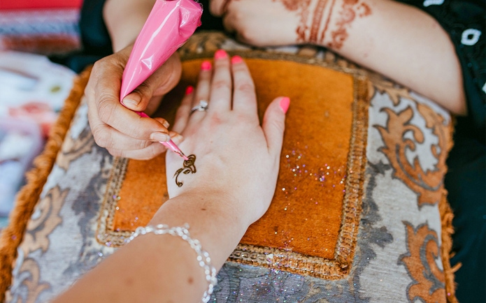 Henna being applied to a hand during an Abu Dhabi desert safari experience.