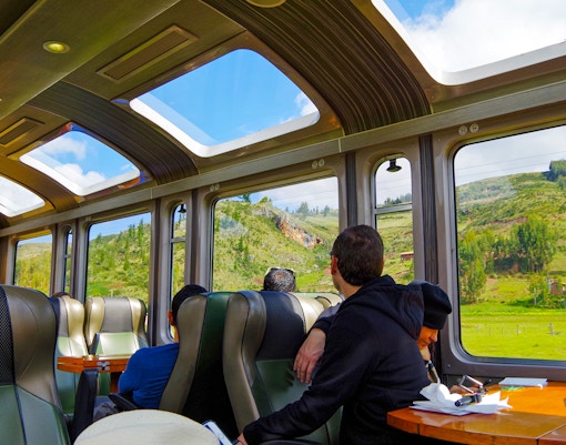 Train passengers viewing scenic landscapes en route to Machu Picchu.