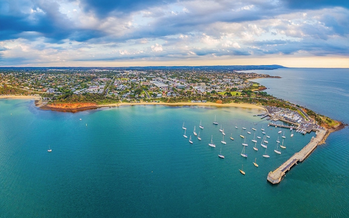 Aerial view of Mornington Peninsula coastline with boats docked at a pier, Australia.