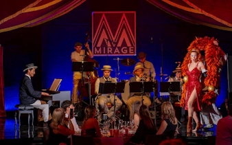 Burlesque performer with feather fans on stage at The Mirage dinner show, Vienna.