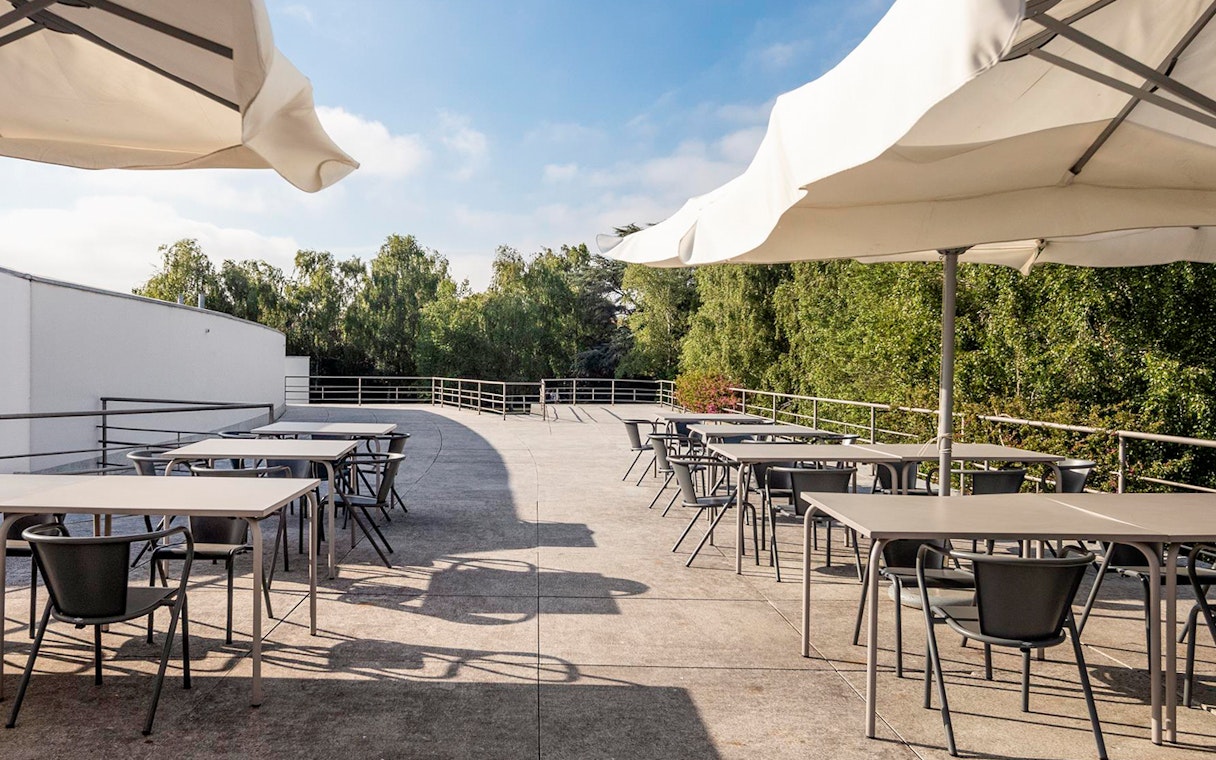 Outdoor terrace with tables and chairs at Serralves, Porto, surrounded by greenery.