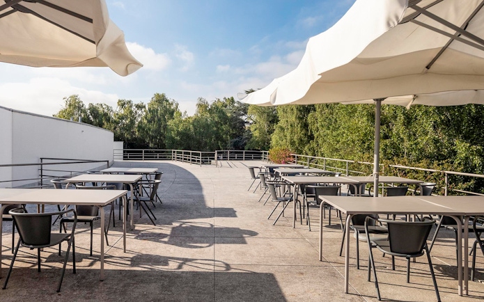 Outdoor terrace with tables and chairs at Serralves, Porto, surrounded by greenery.