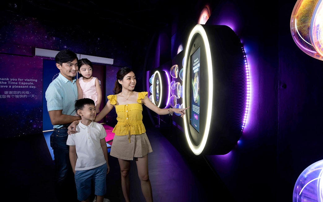 Family exploring interactive exhibit inside the Time Capsule, Singapore.