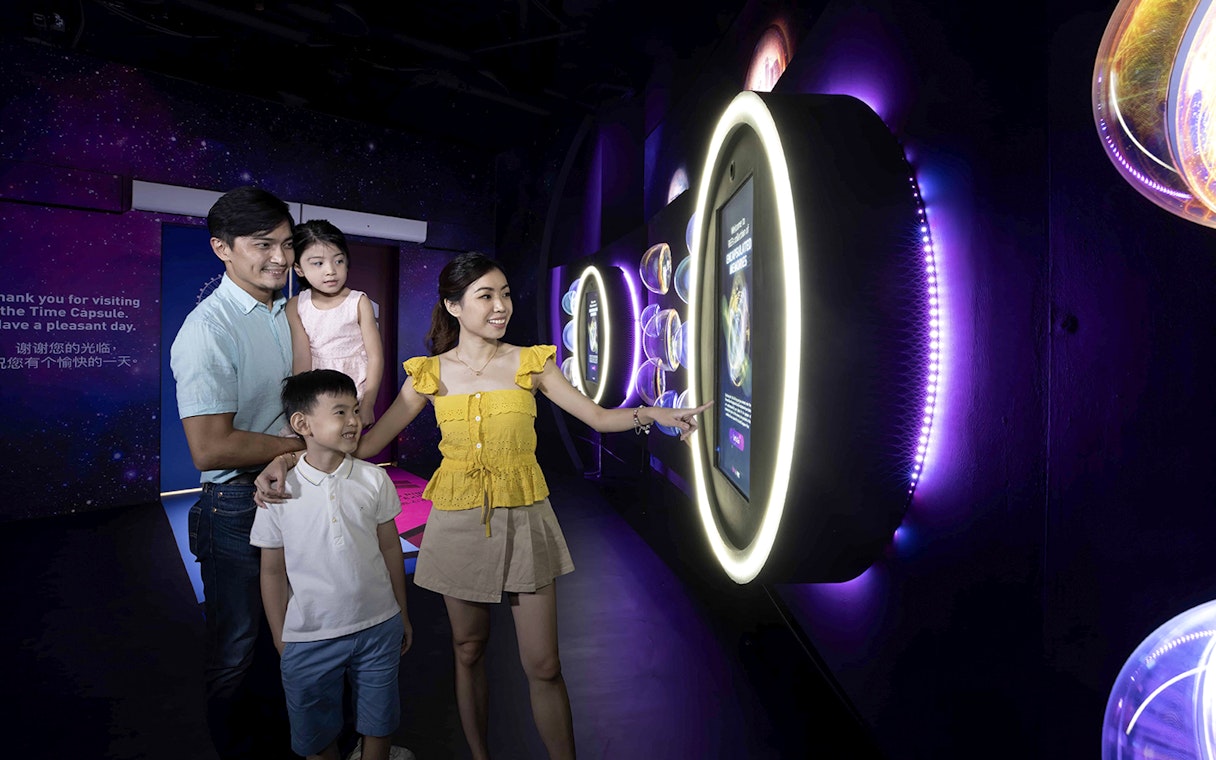Family exploring interactive exhibit inside the Time Capsule, Singapore.