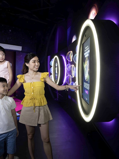 Family exploring interactive exhibit inside the Time Capsule, Singapore.