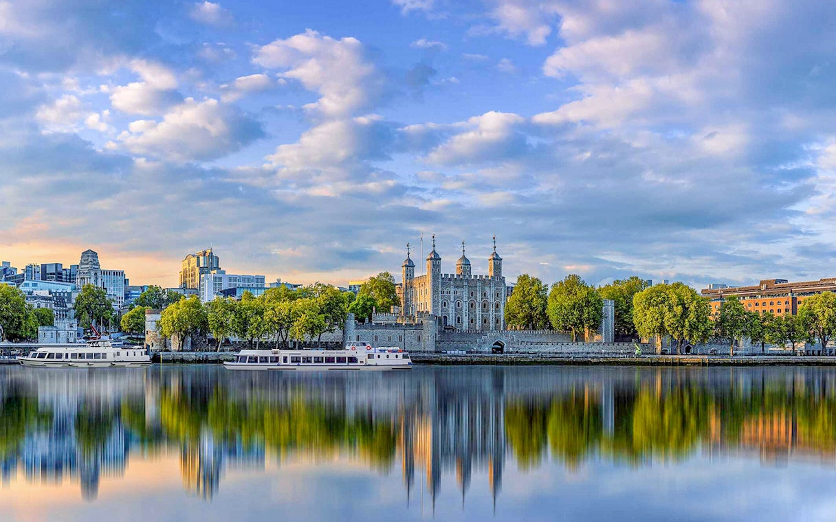 Thames River cruise passing the Tower of London with city skyline in the background.