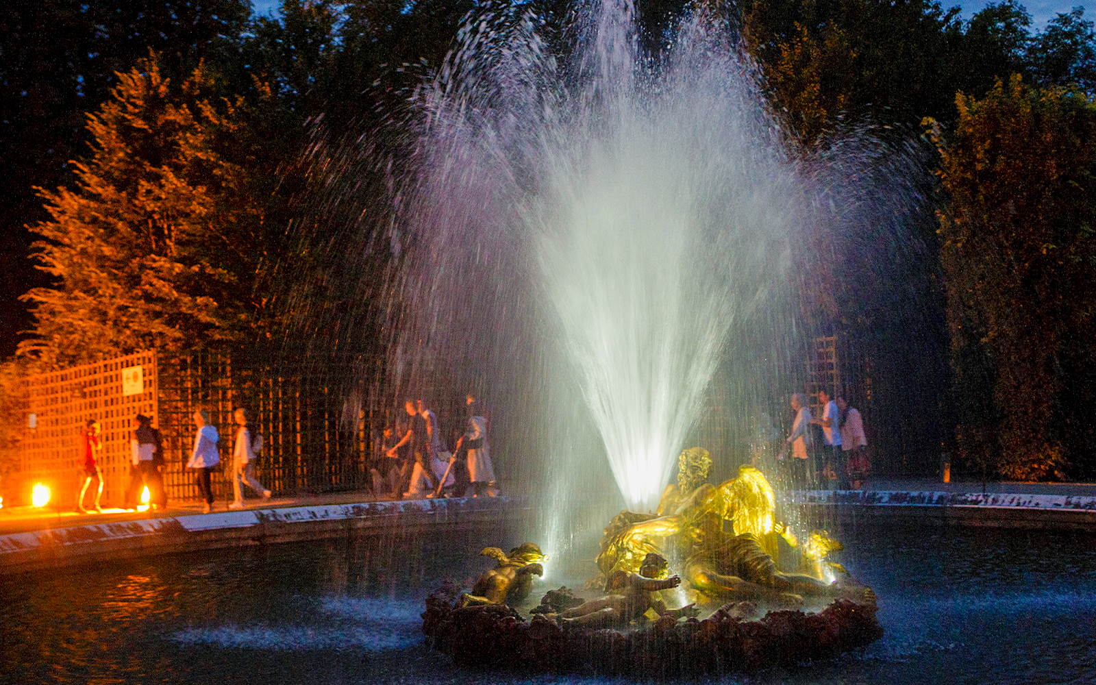 Fountain illuminated at night during the show at the Palace of Versailles.