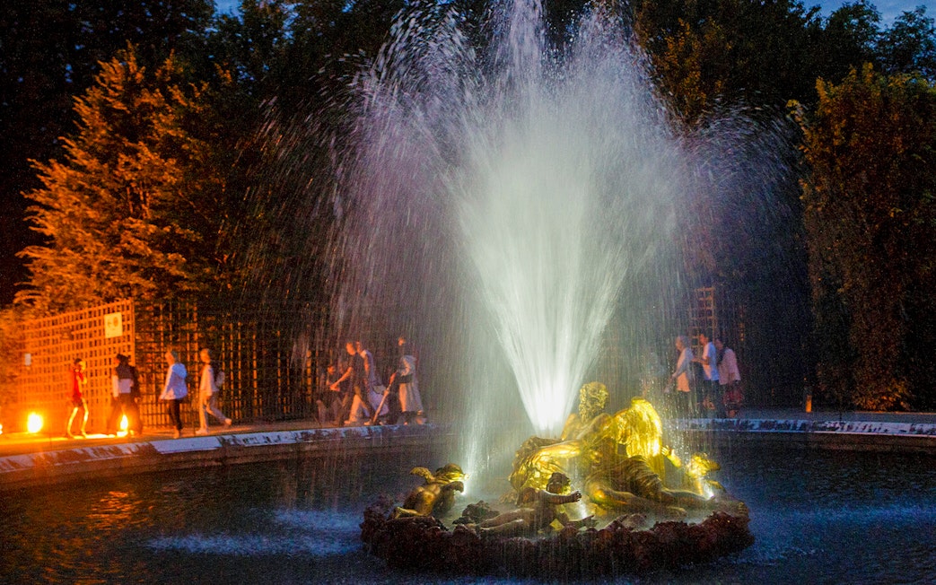 Fountain illuminated at night during the show at the Palace of Versailles.