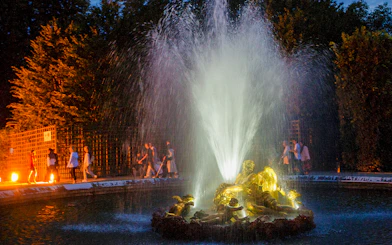 Fountain illuminated at night during the show at the Palace of Versailles.