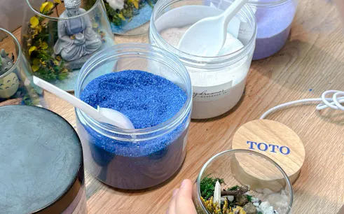 Terrarium workshop materials with colored sand and figurines in Hanoi.
