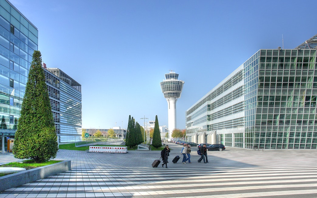 Munich airport control tower with travelers walking, part of Munich City Pass tour.