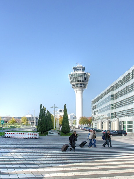 Munich airport control tower with travelers walking, part of Munich City Pass tour.