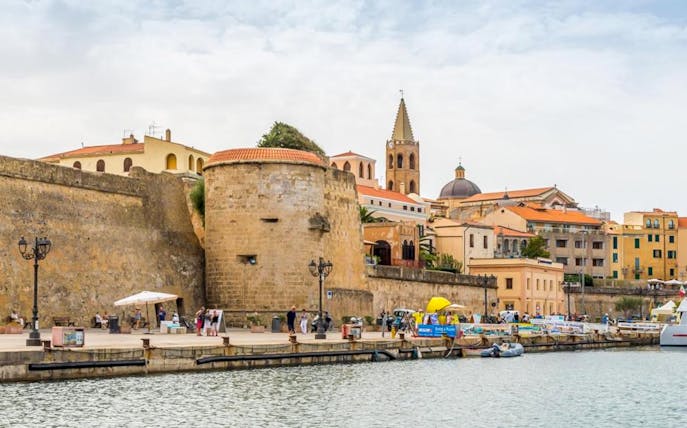 Alghero historic center with medieval walls and bell tower by the waterfront.