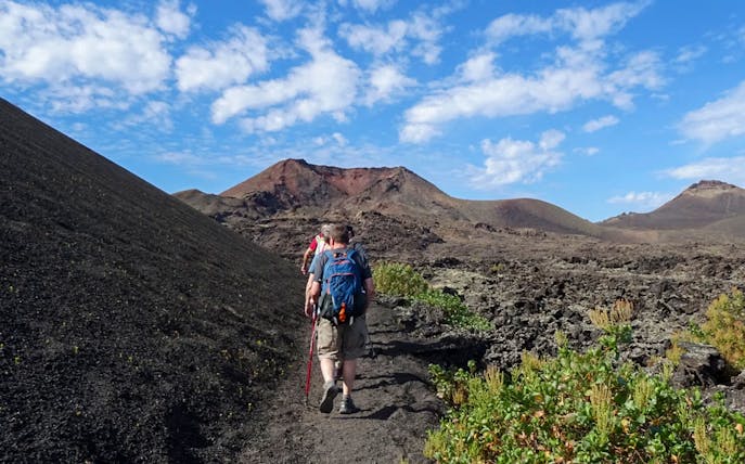 Hikers on a trail through volcanic terrain at Timanfaya National Park, Lanzarote.