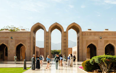 Visitors exploring the Sultan Qaboos Grand Mosque courtyard in Muscat.