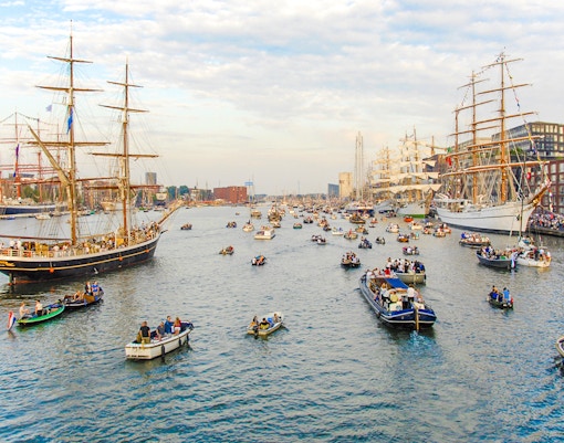 Tall ships and boats in a canal during Sail Amsterdam event.