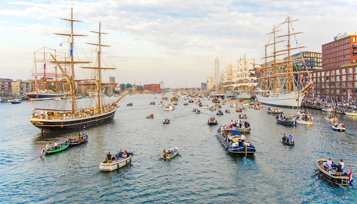 Tall ships and boats in a canal during Sail Amsterdam event.