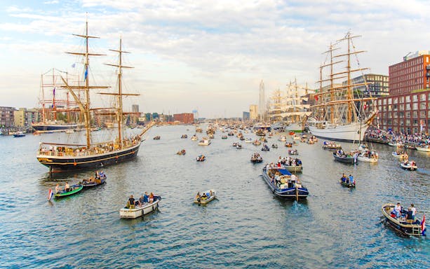 Tall ships and boats in a canal during Sail Amsterdam event.