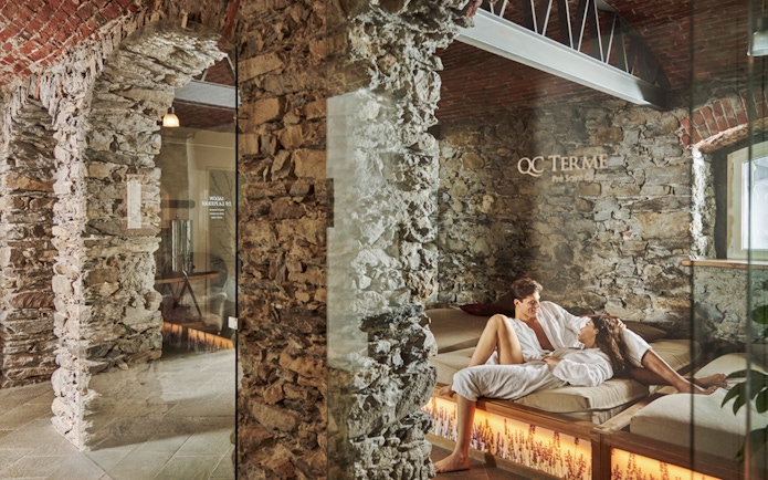 Visitors relaxing at QC Terme Prè Saint Didier Resort & Spa in a stone-walled lounge.