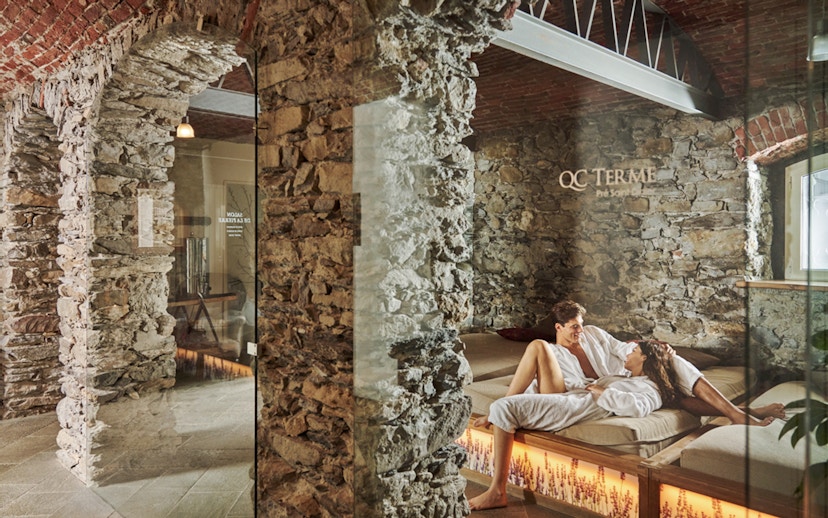 Visitors relaxing at QC Terme Prè Saint Didier Resort & Spa in a stone-walled lounge.
