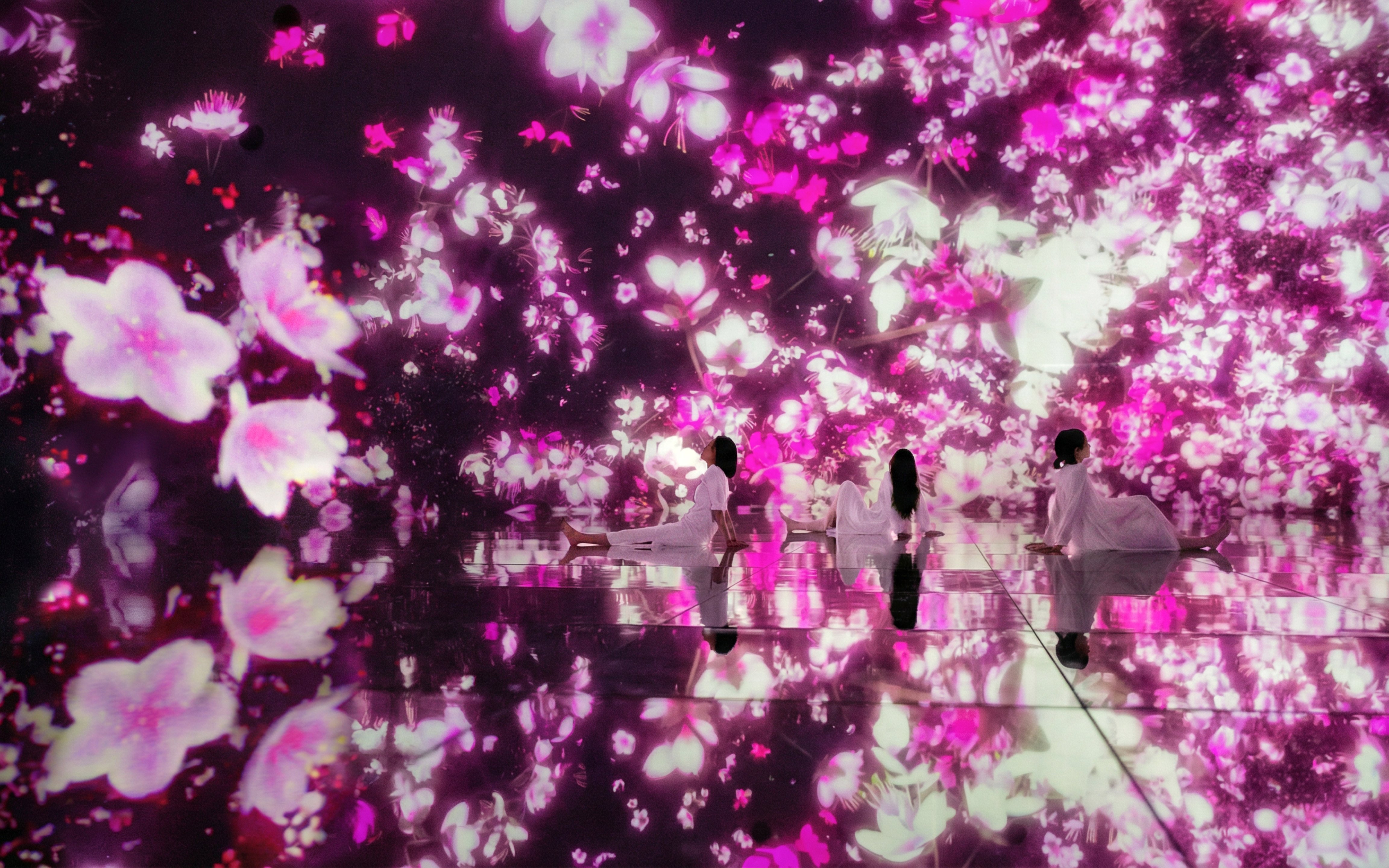Visitors in immersive floral digital art at teamLab Planets Tokyo.