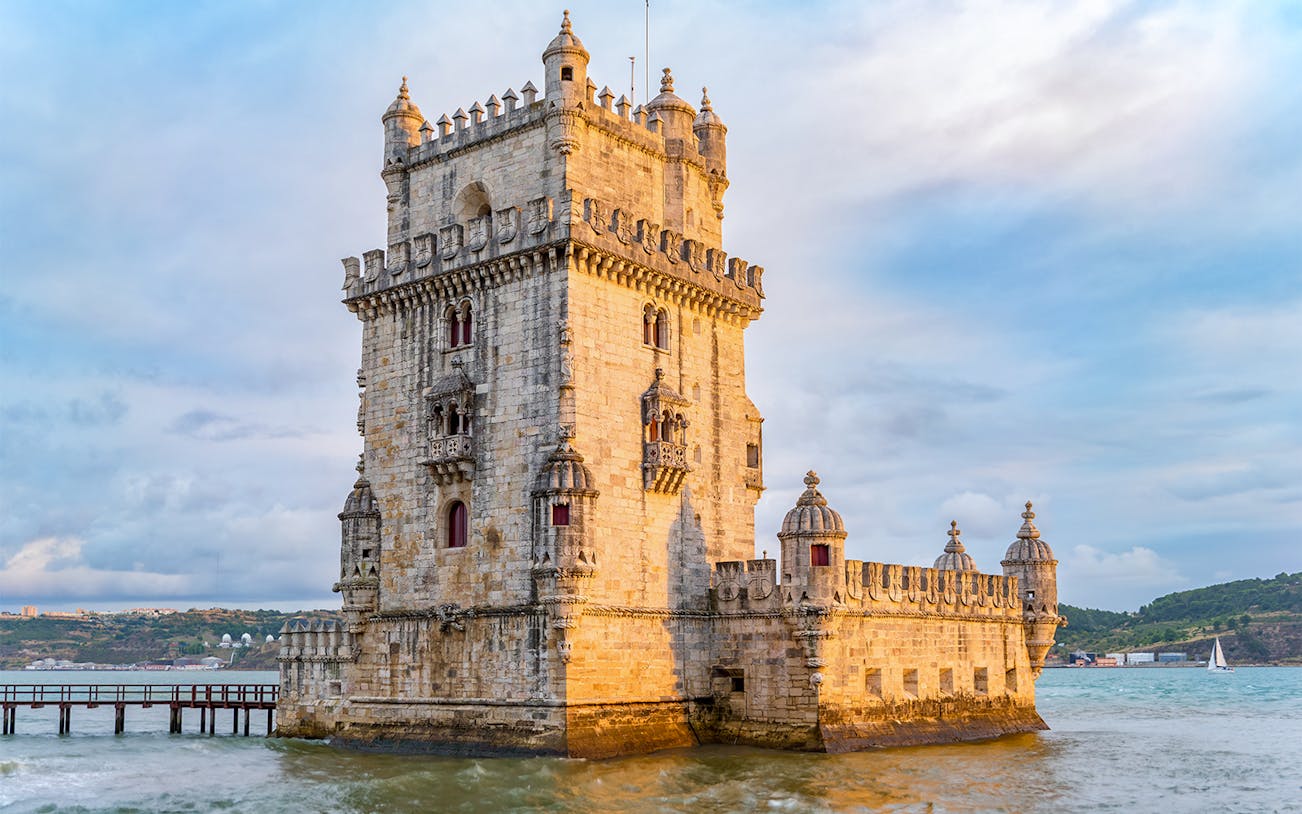 Belém Tower in Lisbon, Portugal, with surrounding water and distant hills.