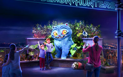 Visitors interacting with a large blue animated creature at Netflix House Philadelphia, Kpop Demon Hunters exhibit.