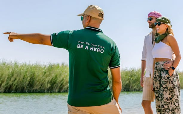 Guide pointing out sights to tourists by a river.