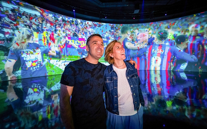 Couple enjoying interactive exhibit at Camp Nou Barça Museum.