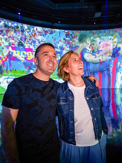 Couple enjoying interactive exhibit at Camp Nou Barça Museum.